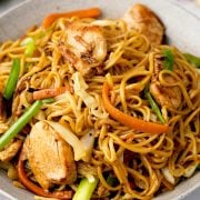 Close-up of a bowl filled with Chicken Chow Mein noodles, featuring tender chicken strips, stir-fried vegetables, and noodles tossed in a savory sauce, garnished with chopped green onions.