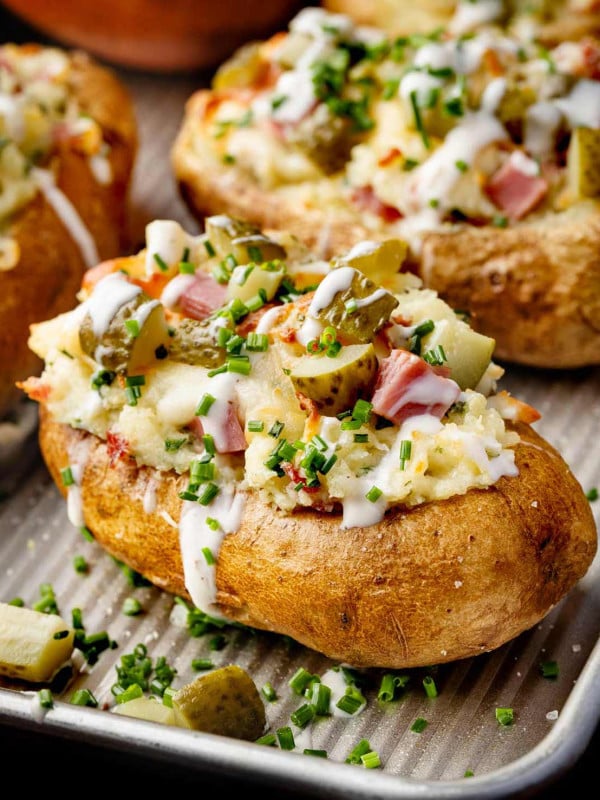 A batch of Dill Pickle and Ham Twice Baked Potatoes sits on a baking sheet.
