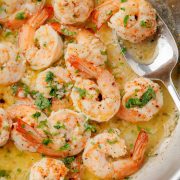Overhead view of a skillet filled with garlic butter shrimp scampi, garnished with fresh parsley.
