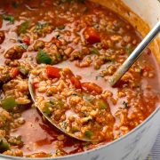 A pot of stuffed pepper soup, filled with bell peppers, tomatoes, and ground meat. A ladle rests inside the pot, ready for serving.