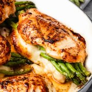 Close-up of Asparagus Stuffed Chicken Breast in a skillet, showing juicy golden-brown chicken, melted cheese, and vibrant green asparagus spears.