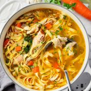 Overhead view of a pot filled with homemade chicken noodle soup with a ladle.