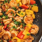 Kung Pao Shrimp with bell peppers, peanuts, and green onions in a flavorful sauce in the skillet.