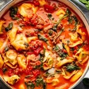 A hearty pot of sausage tortellini soup, featuring tender tortellini, crumbled sausage, fresh spinach, and tomatoes in a rich, creamy tomato broth.