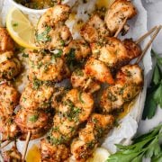 Juicy Cowboy Butter Chicken Skewers garnished with fresh parsley and served with lemon slices, featuring a zesty butter sauce for dipping.