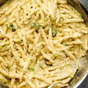 A skillet filled with creamy broccoli pasta coated in a rich cheese sauce.