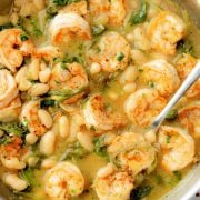 A skillet of lemony shrimp and bean stew with plump shrimp, white beans, spinach, and a flavorful broth.