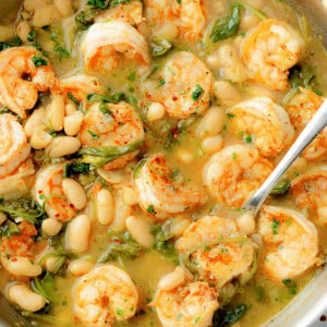 A skillet of lemony shrimp and bean stew with plump shrimp, white beans, spinach, and a flavorful broth.