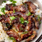 Beef in oyster sauce served over steamed white rice and topped with sliced green onions.