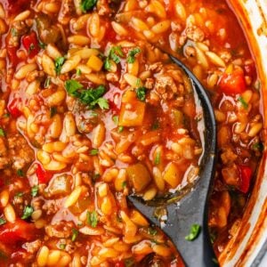 Close-up of hearty stuffed pepper orzo soup with ground beef, peppers, and fresh parsley.
