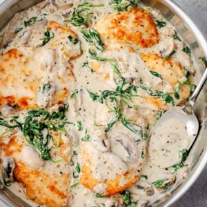 Creamy Chicken Florentine with mushrooms and spinach in garlic Parmesan sauce in a skillet.