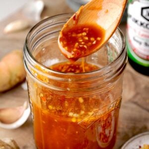 Homemade stir fry sauce in a glass jar with a wooden spoon, showing a glossy mix of soy sauce, garlic, ginger, and red pepper flakes โ perfect for quick Asian-inspired dishes.