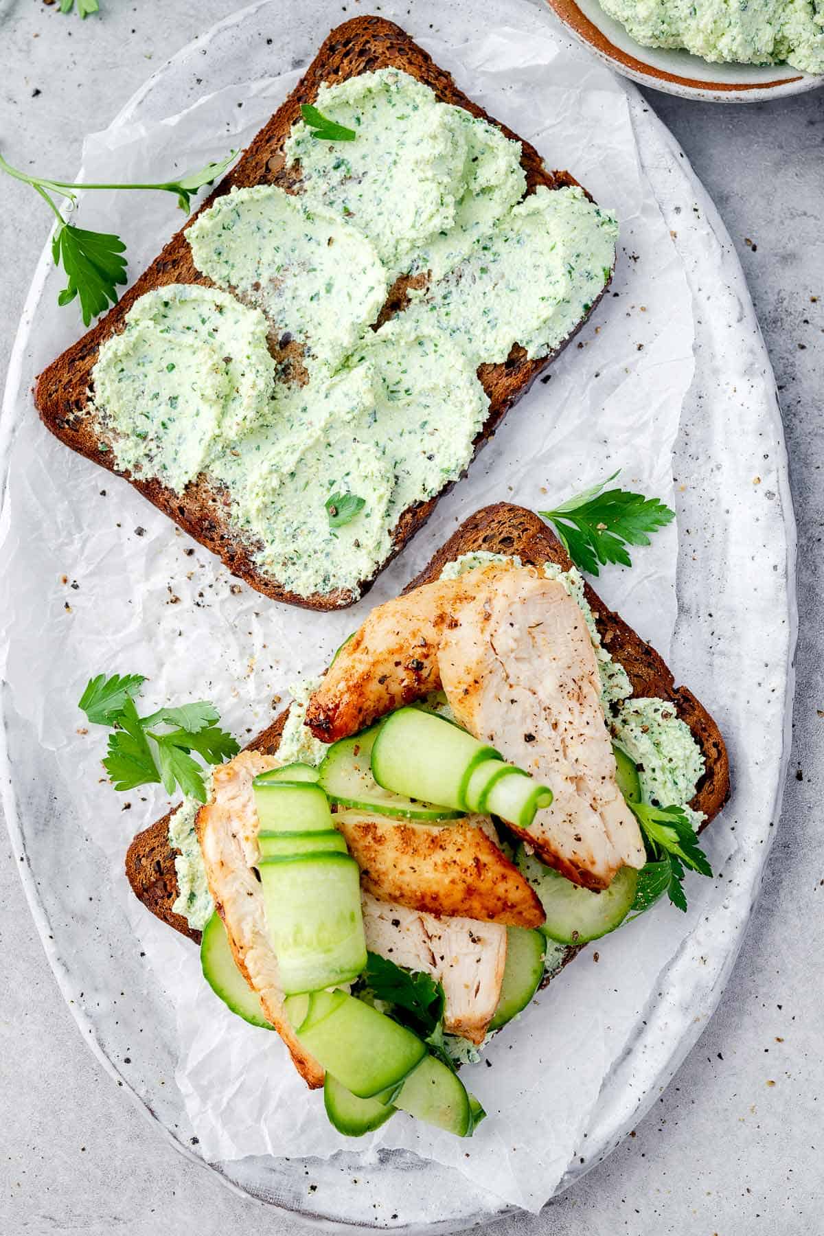 High-protein chicken cucumber cottage cheese toast with herbed cottage cheese spread, grilled chicken slices, fresh cucumber ribbons, and parsley on whole grain bread.
