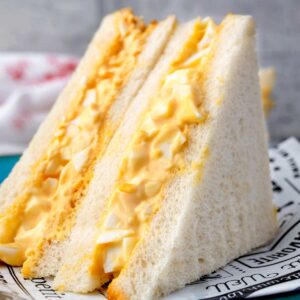 Japanese egg sandwich (tamago sando) made with creamy egg salad filling layered between soft white milk bread, cut in half and served on a plate.
