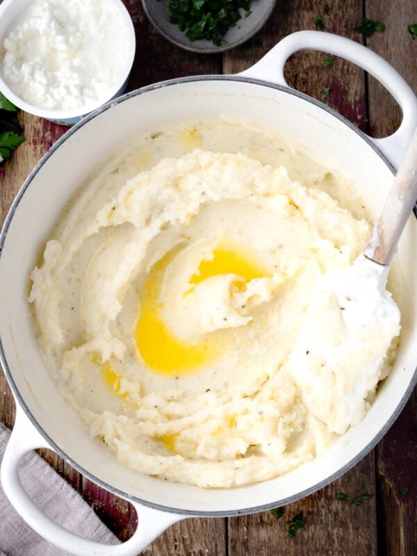 Creamy cottage cheese mashed potatoes in a white pot, swirled with melted butter and mixed until smooth and fluffy.