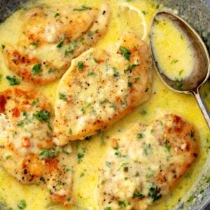 Creamy lemon chicken in skillet with golden seared chicken breasts, garlic, parsley, and buttery lemon sauce.