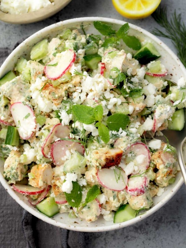 Healthy tzatziki chicken salad with cucumber, radishes, fresh herbs, feta cheese, and creamy yogurt dressing in a bowl.
