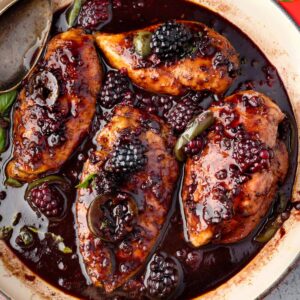 Skillet blackberry jalapeรฑo chicken with a sweet and savory blackberry balsamic glaze, fresh blackberries, basil, and lime wedges.