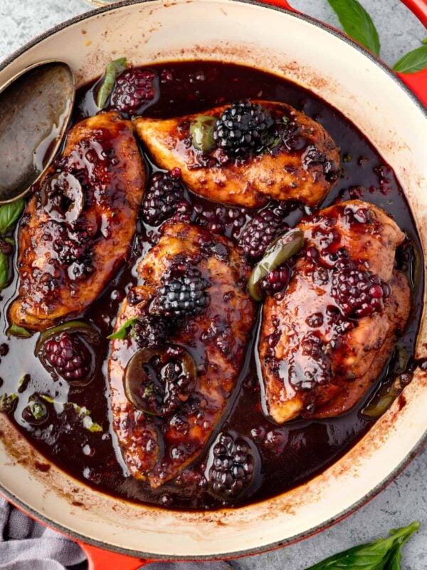 Skillet blackberry jalapeรฑo chicken with a sweet and savory blackberry balsamic glaze, fresh blackberries, basil, and lime wedges.
