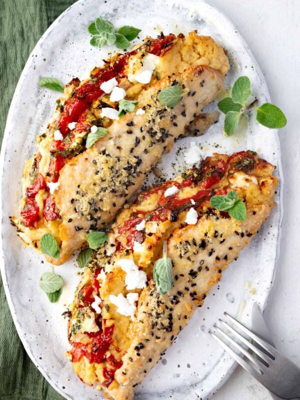 Overhead view of Mediterranean Hummus Chicken Pockets stuffed with roasted garlic hummus, feta cheese, roasted red peppers, and fresh parsley, topped with a crispy crust.