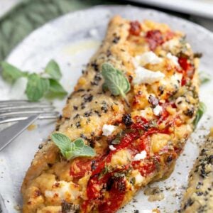 Mediterranean Hummus Chicken Pocket filled with roasted garlic hummus, feta cheese, roasted red peppers, and fresh parsley, baked with a crispy Parmesan and sesame seed topping.