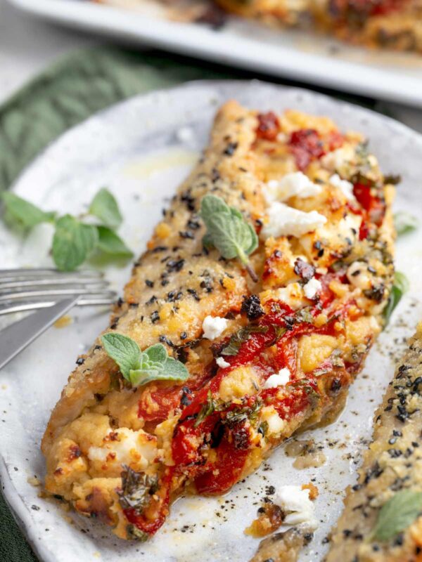 Mediterranean Hummus Chicken Pocket filled with roasted garlic hummus, feta cheese, roasted red peppers, and fresh parsley, baked with a crispy Parmesan and sesame seed topping.