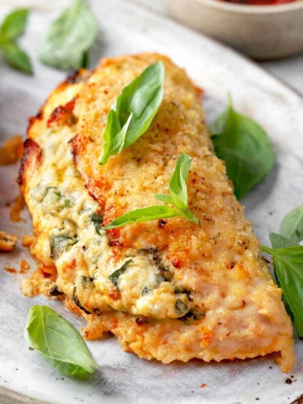 Crispy baked Boursin stuffed chicken breast with a creamy spinach and herb cheese filling, served hot and garnished with fresh basil leaves.