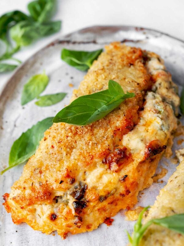 Crispy baked Boursin stuffed chicken breast with a creamy spinach and herb cheese filling, served hot and garnished with fresh basil leaves.