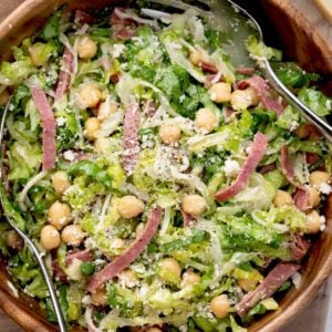 La Scala Chopped Salad with shredded romaine lettuce, chickpeas, salami, Parmesan cheese, and Italian dressing tossed together in a wooden serving bowl.