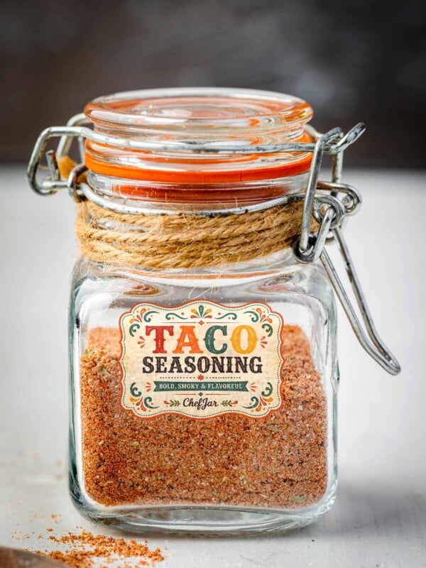 Homemade Old El Paso taco seasoning copycat stored in a glass spice jar with a rustic label, filled with a flavorful blend of chili powder, cumin, paprika, and spices.