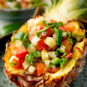 Pineapple Pico de Gallo served in a hollowed pineapple half, made with fresh pineapple, diced tomatoes, onion, jalapeño, cilantro, and lime juice for a colorful tropical salsa.