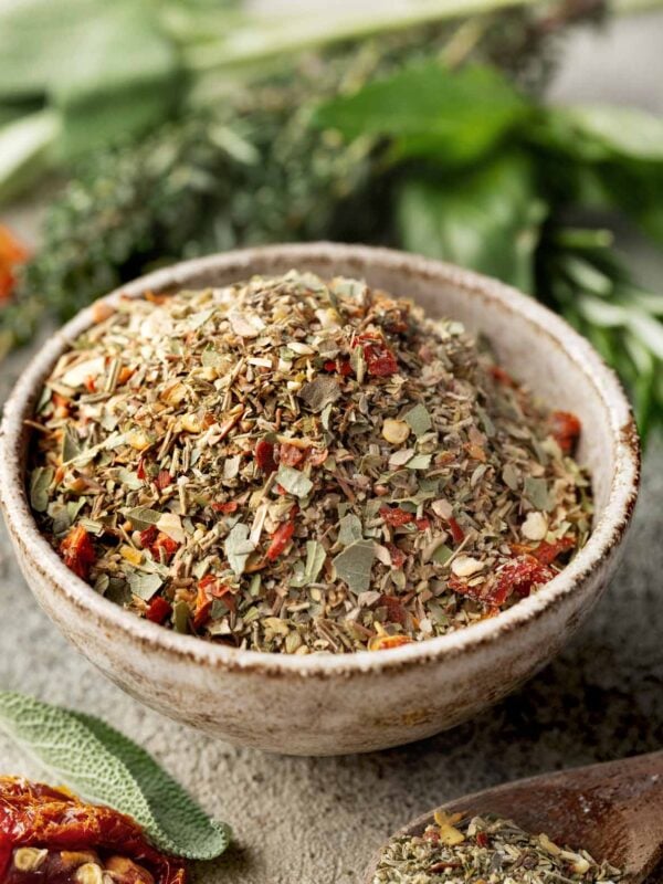 Homemade Tuscan seasoning blend in a rustic bowl, made with dried Italian herbs, garlic, onion, rosemary, sage, and chopped sun-dried tomatoes. Perfect for chicken, pasta, vegetables, and soups.
