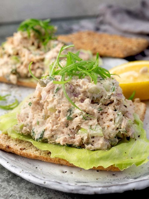 Easy tuna salad with celery, dill pickles, red onion, and fresh herbs served on lettuce and whole grain bread.