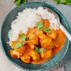 Easy Instant Pot butter chicken in a creamy tomato sauce served over white rice and garnished with fresh cilantro.
