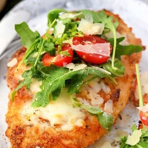 Crispy baked Chicken Milanese topped with melted mozzarella, arugula, cherry tomatoes, and shaved Parmesan.