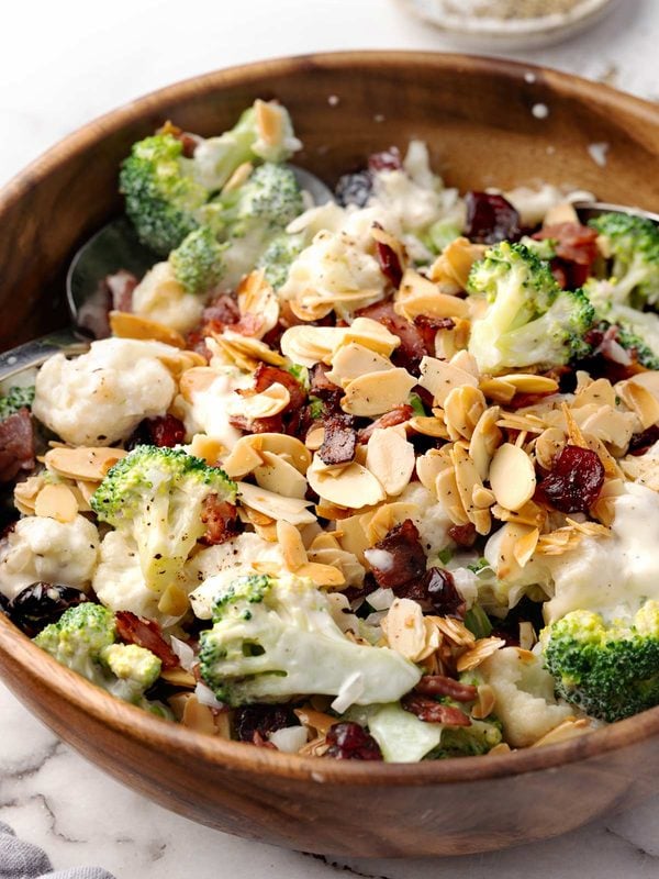 Creamy broccoli and cauliflower salad with crispy turkey bacon, dried cranberries, toasted sliced almonds, and red onion.