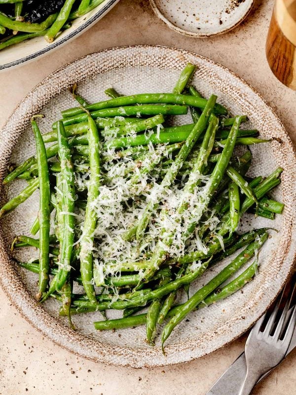 Cacio e pepe green beans topped with grated Pecorino Romano and freshly cracked black pepper.