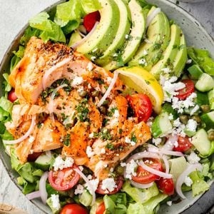 Salmon and avocado salad with romaine lettuce, cherry tomatoes, cucumber, feta, capers, red onion, and lemon.