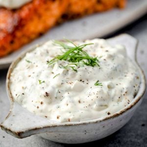 Homemade tartar sauce for salmon with fresh dill and black pepper in a small serving bowl.