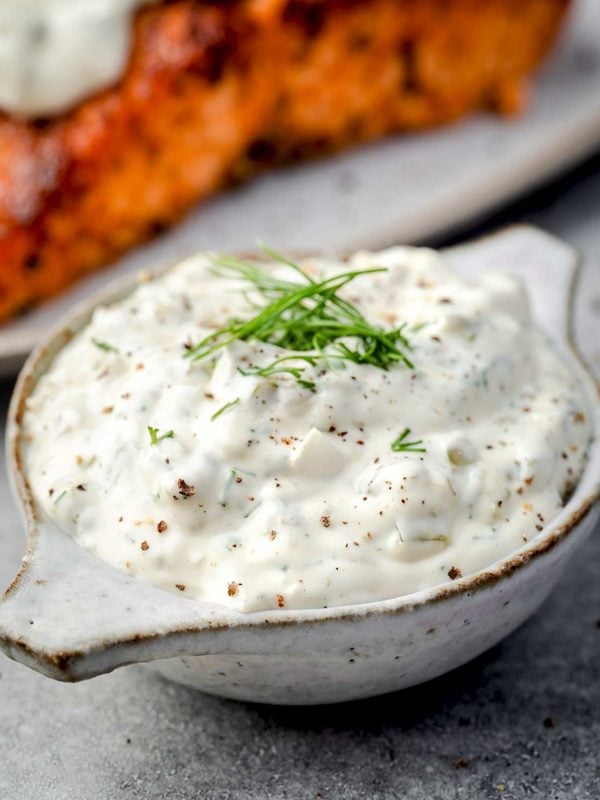 Homemade tartar sauce for salmon with fresh dill and black pepper in a small serving bowl.