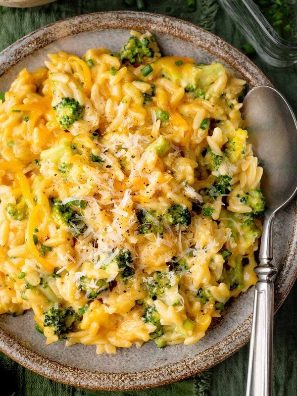 Creamy Broccoli Cheddar Orzo with tender broccoli florets, sharp cheddar cheese, and freshly grated Parmesan in a rustic ceramic bowl.