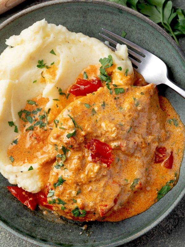 Creamy Paprika Chicken served with buttery mashed potatoes, smothered in a rich paprika cream sauce with sun-dried tomatoes and garnished with fresh parsley.